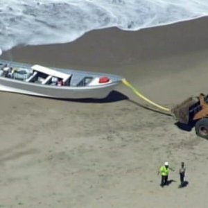 Authorities used a tractor to pull a Panga boat from the shore at Pescadero