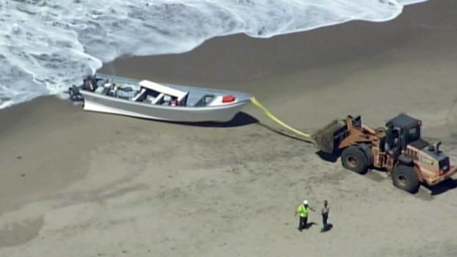 Authorities used a tractor to pull a Panga boat from the shore at Pescadero